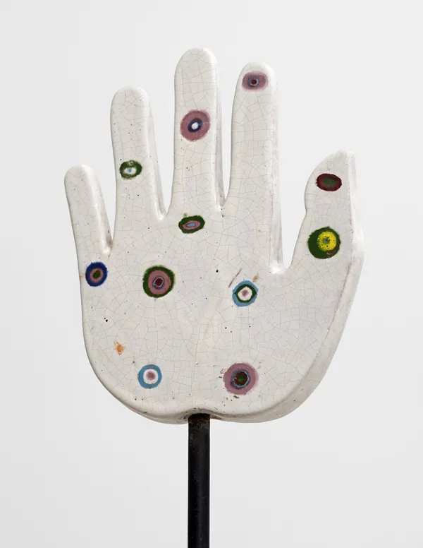 Detalhe da mesma escultura: mão cerâmica branca com círculos coloridos