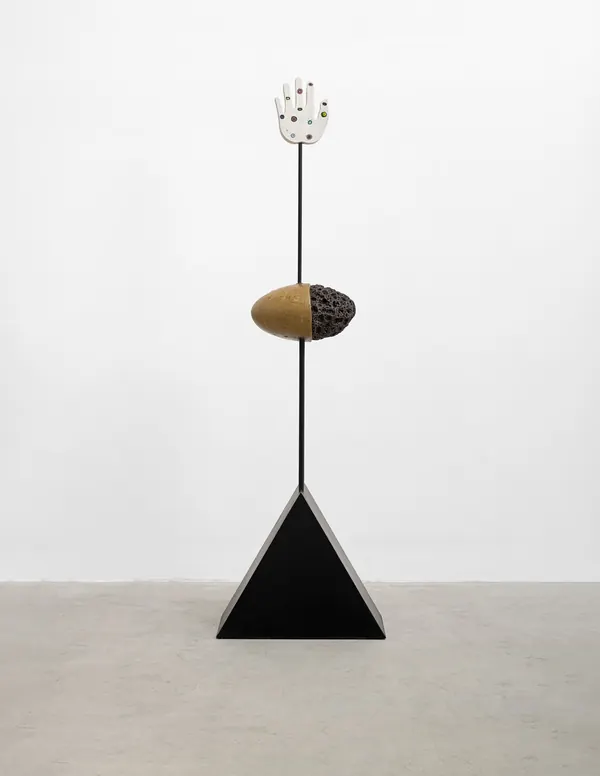 Escultura de Megumi Yuasa: mão cerâmica no alto de uma haste, com forma oval e base triangular